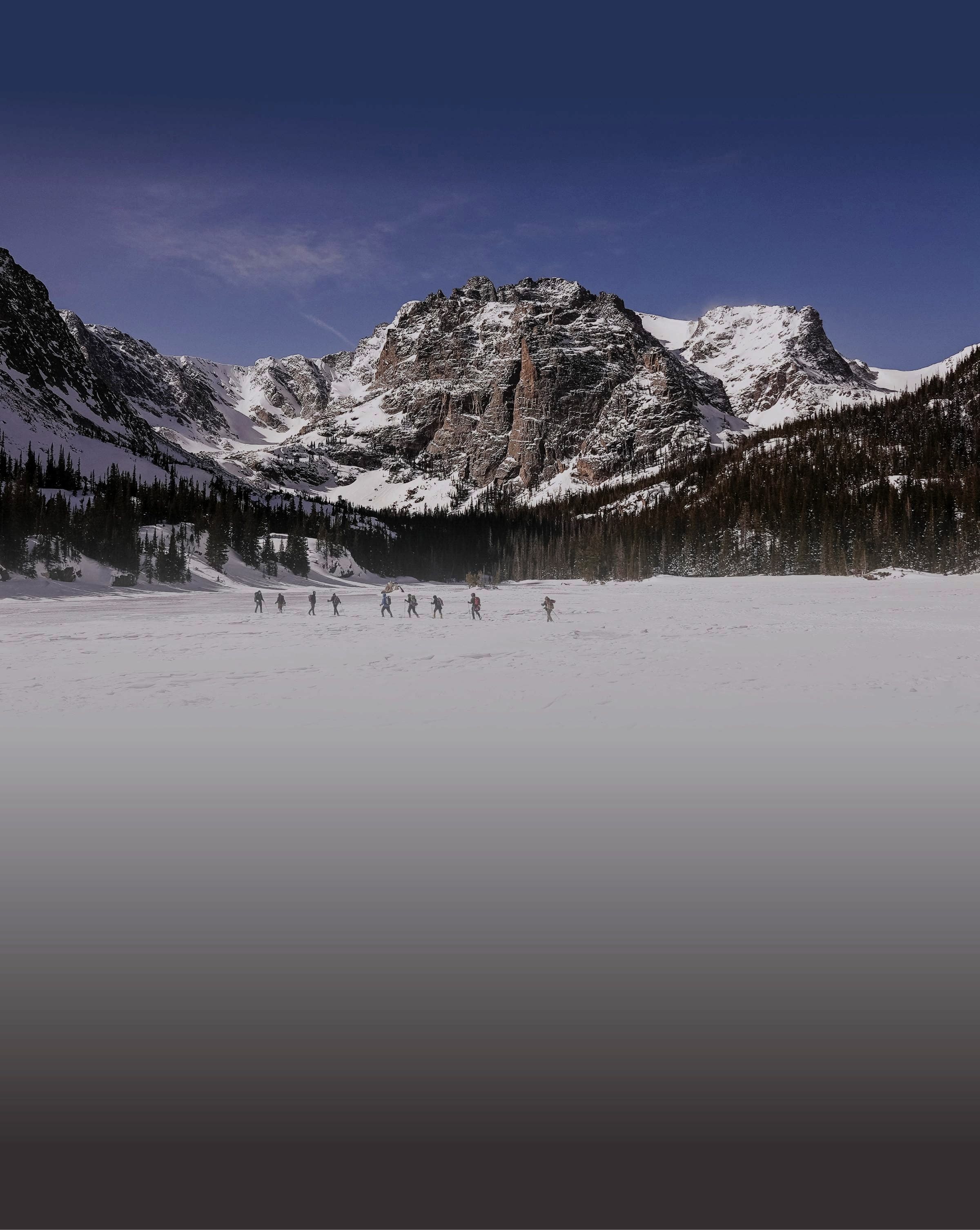 The team crossing frozen Sky Pond beneath the peaks of Rocky Mountain National Park